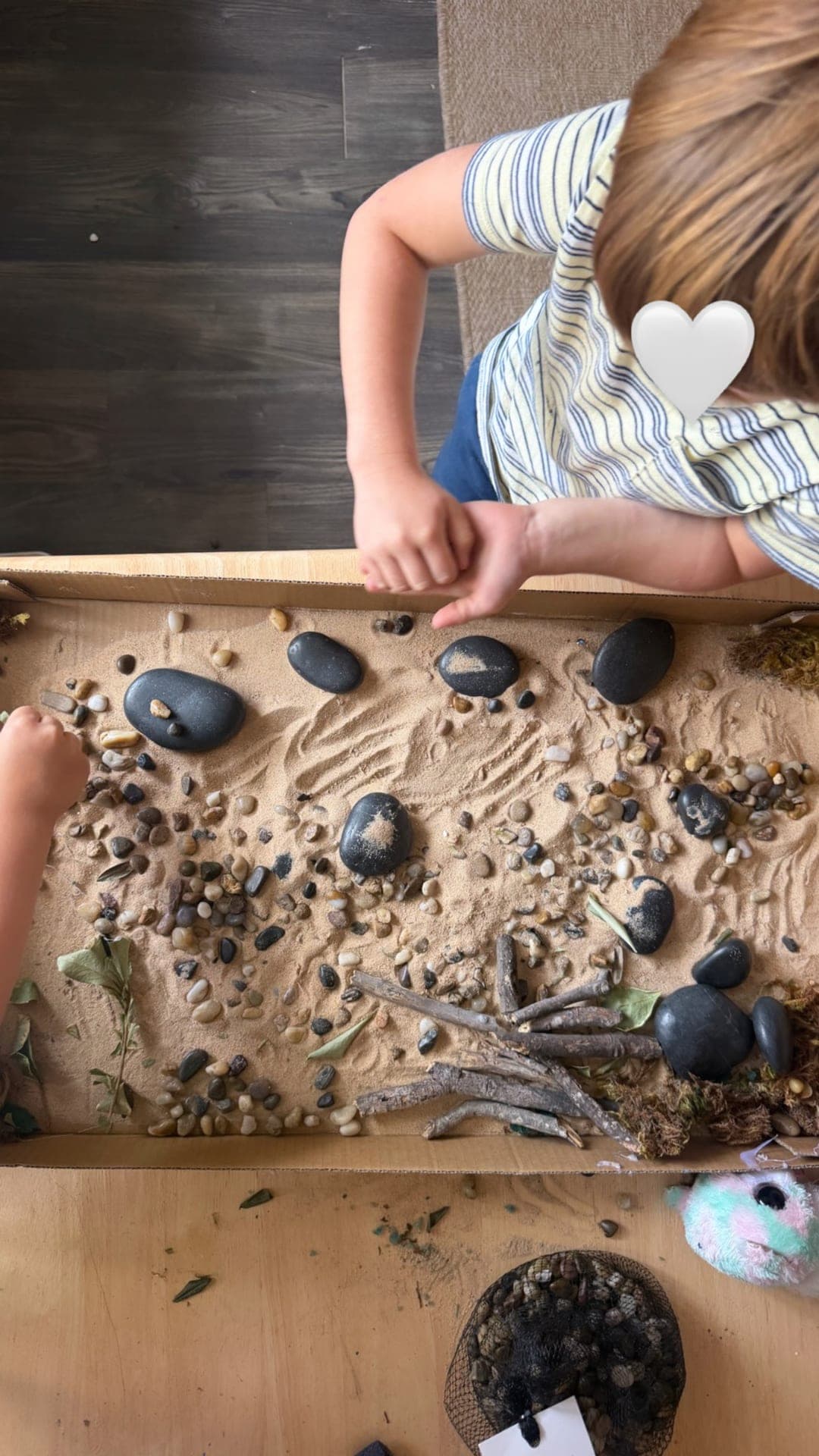 Primary — sensory tray with sand, stones, and natural materials