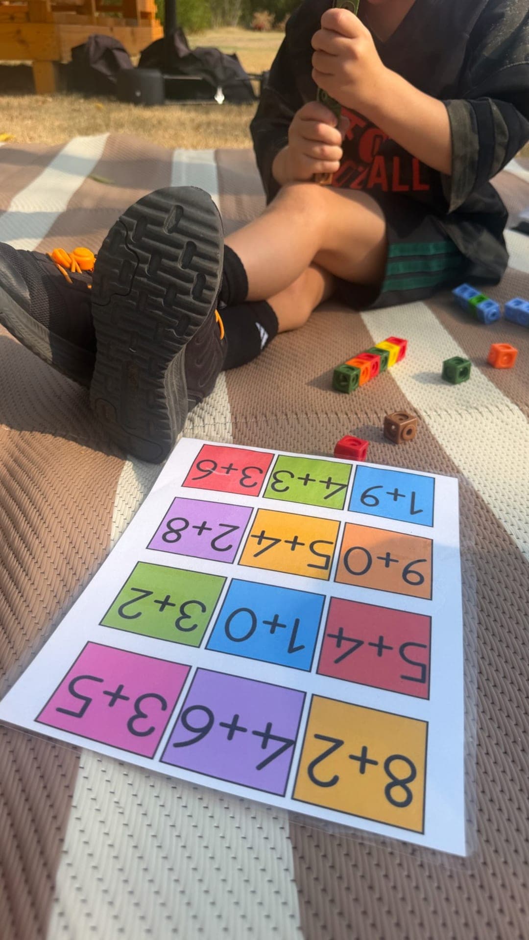 Outdoor addition practice with linking cubes on the striped mat